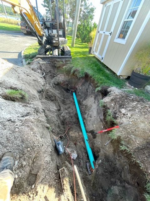 a green pipe is in the dirt next to a shed