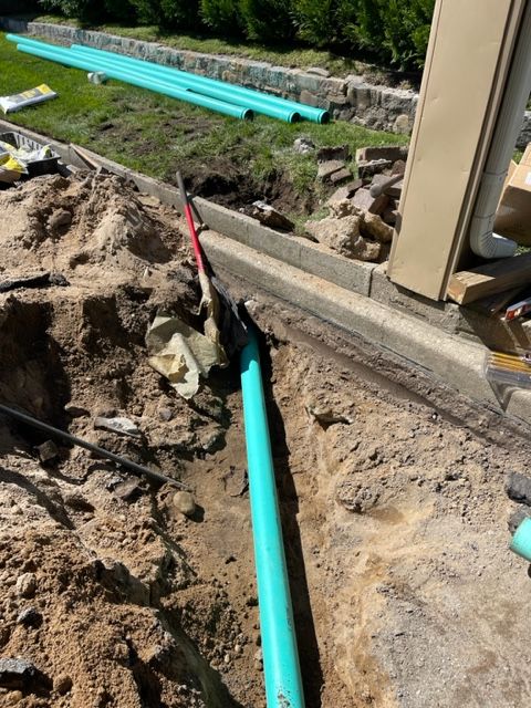 a green pipe is sitting in the dirt next to a shovel .