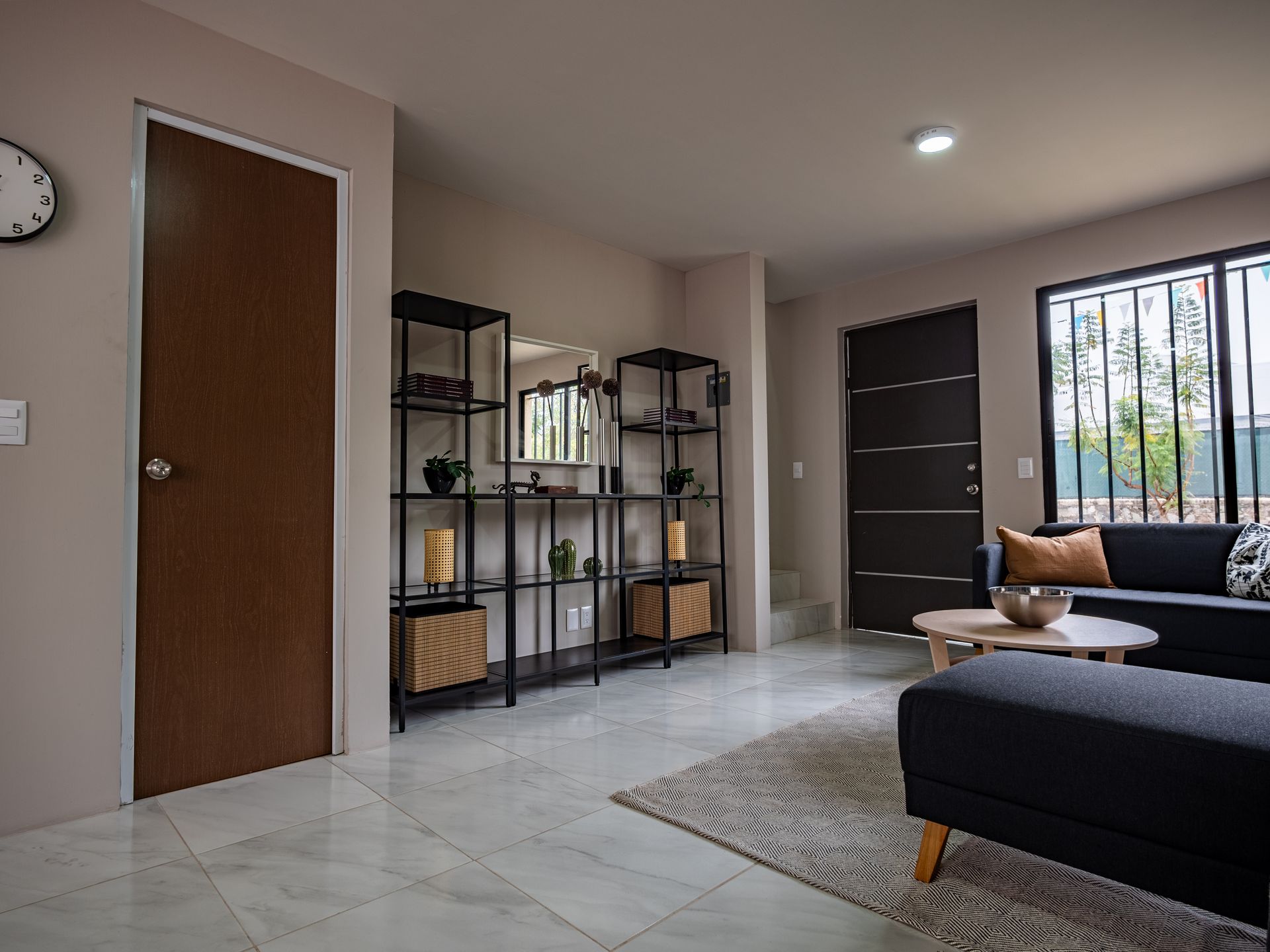 Una sala de estar con sofá, otomana, mesa y espejo.