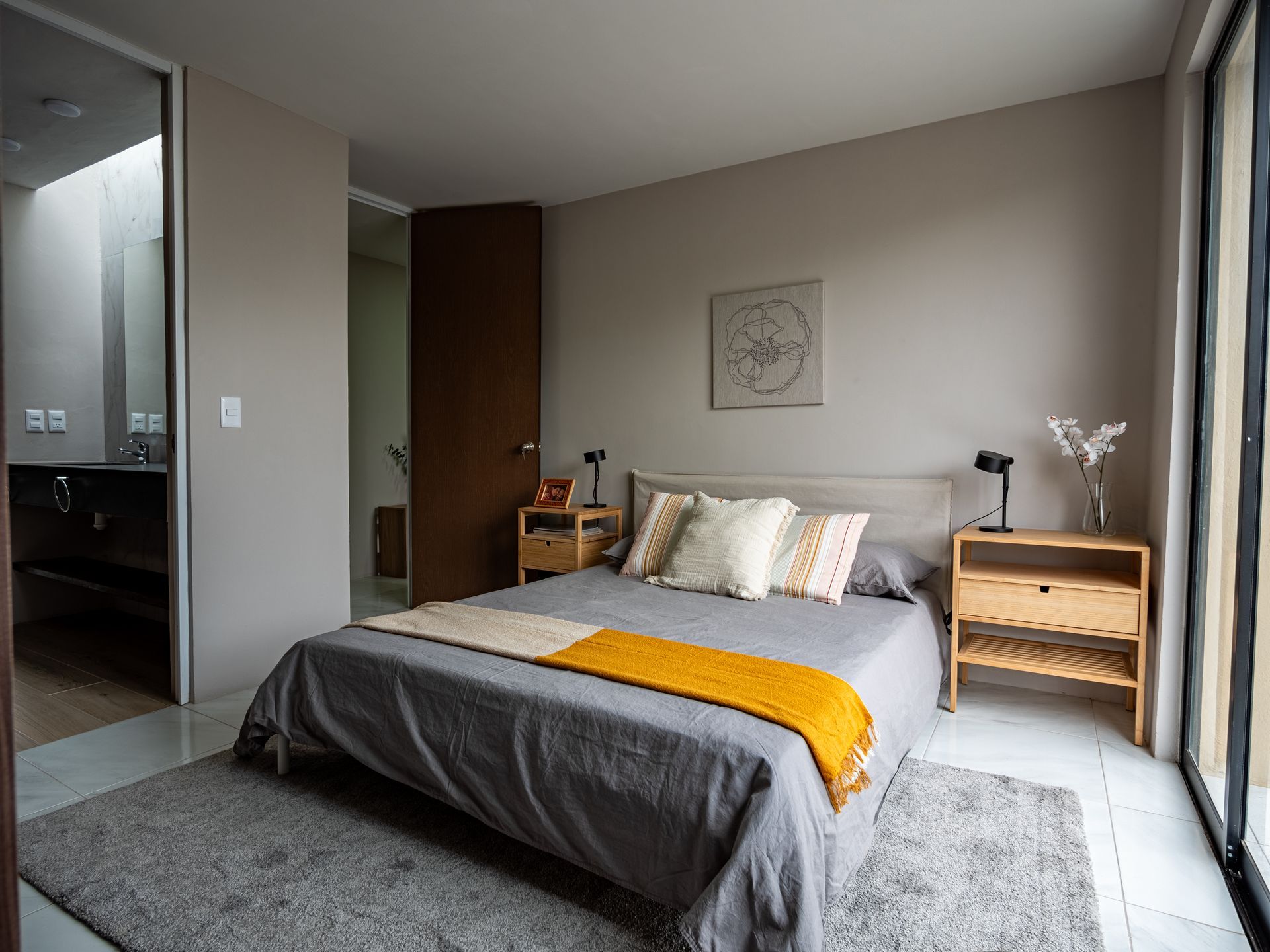 Un dormitorio con una cama grande, mesitas de noche y una ventana grande.