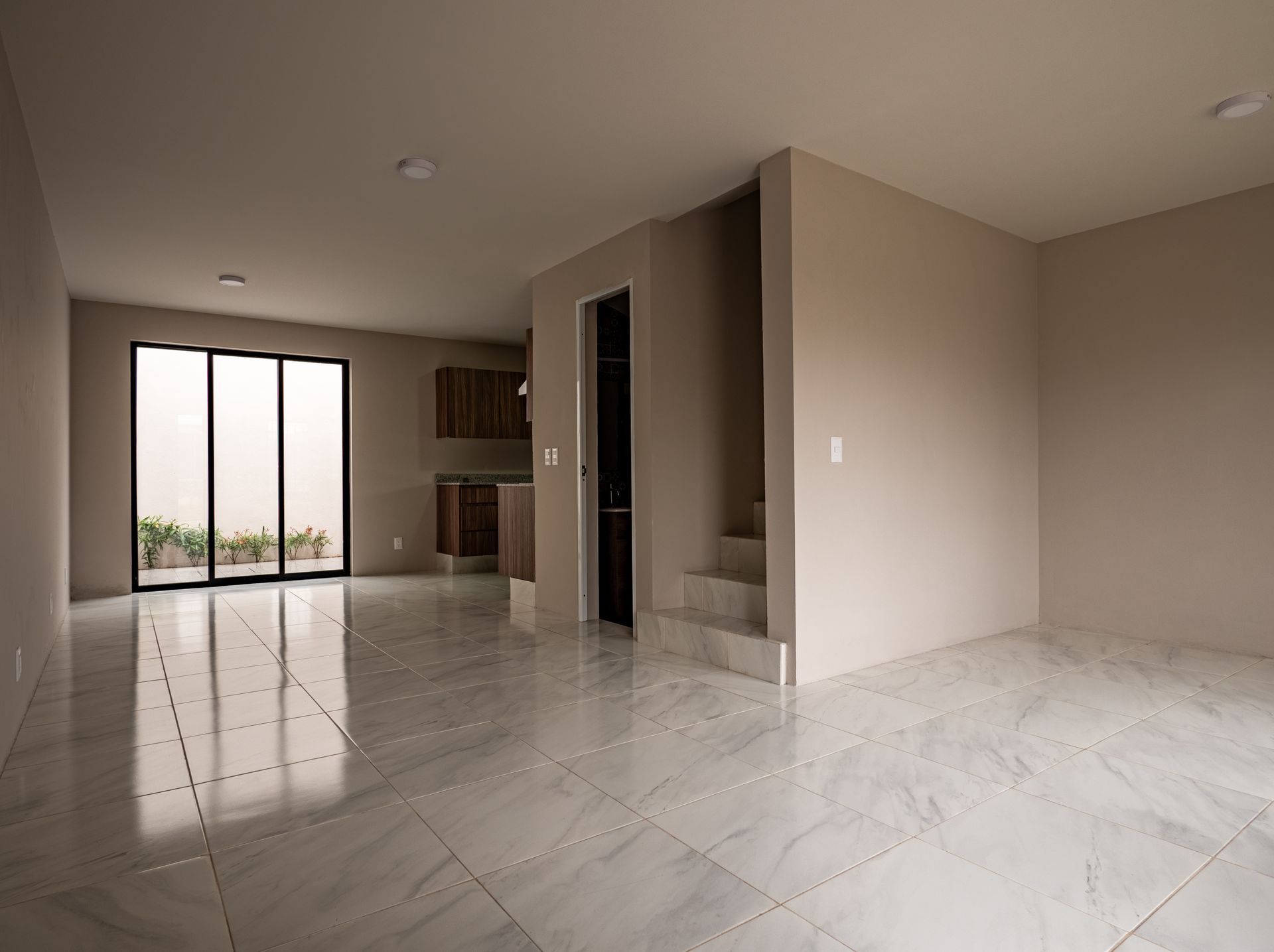 Una habitación vacía con suelo de mármol y escaleras en una casa.