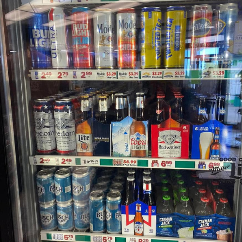 A refrigerator filled with bottles and cans of beer including bud light