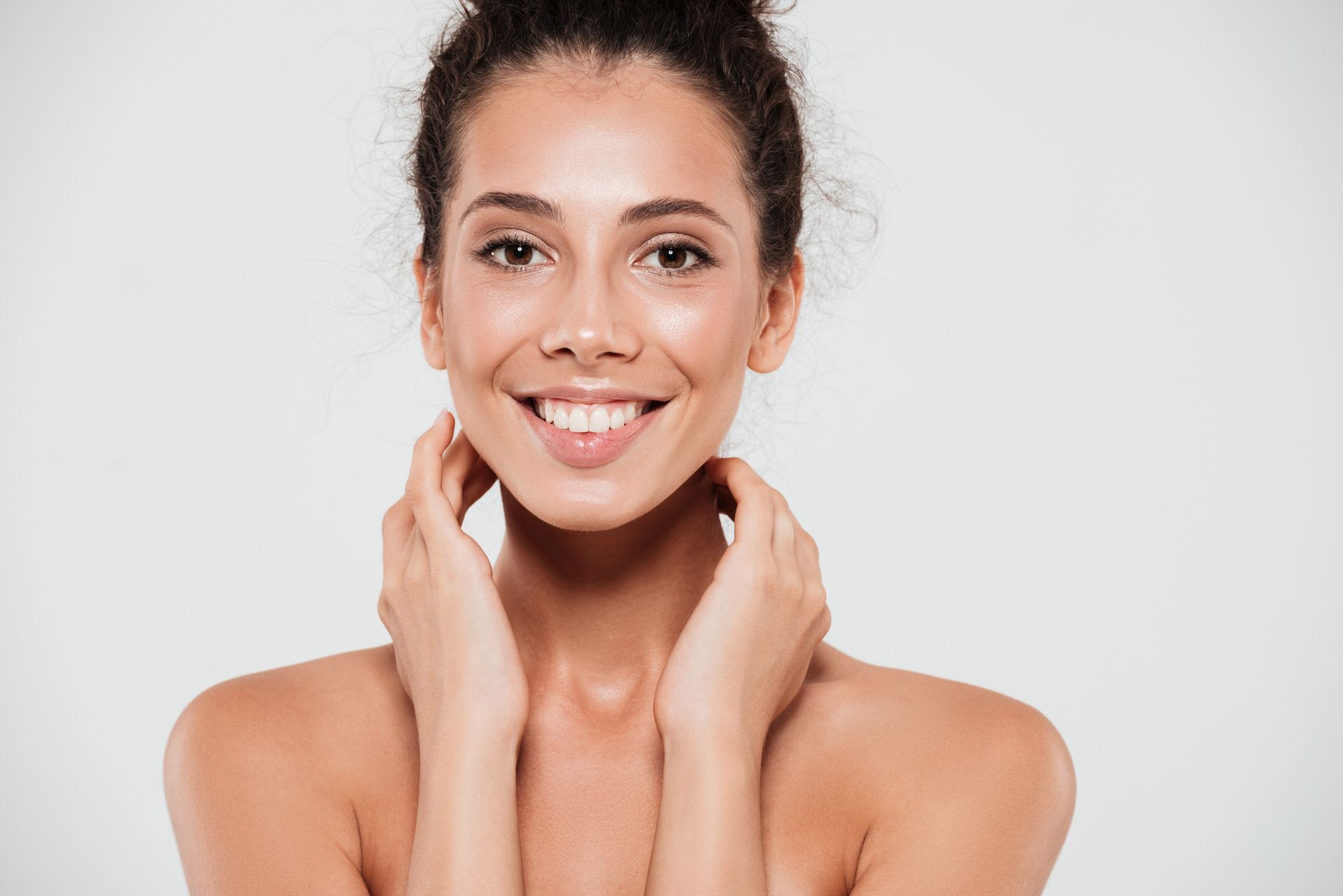 Portrait of a smiling woman touching her face over gray background