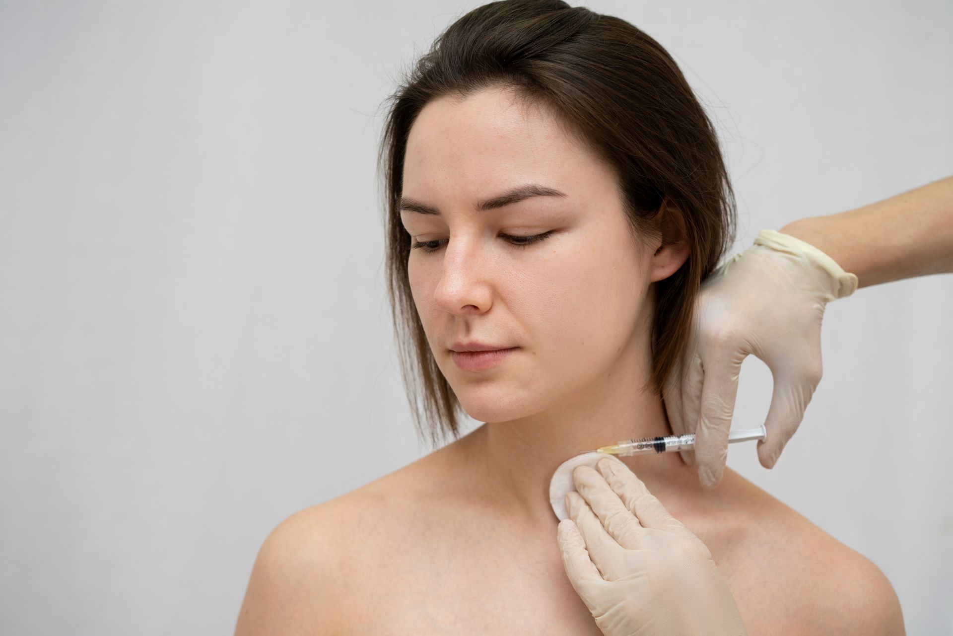 A woman is getting a botox injection in her neck.