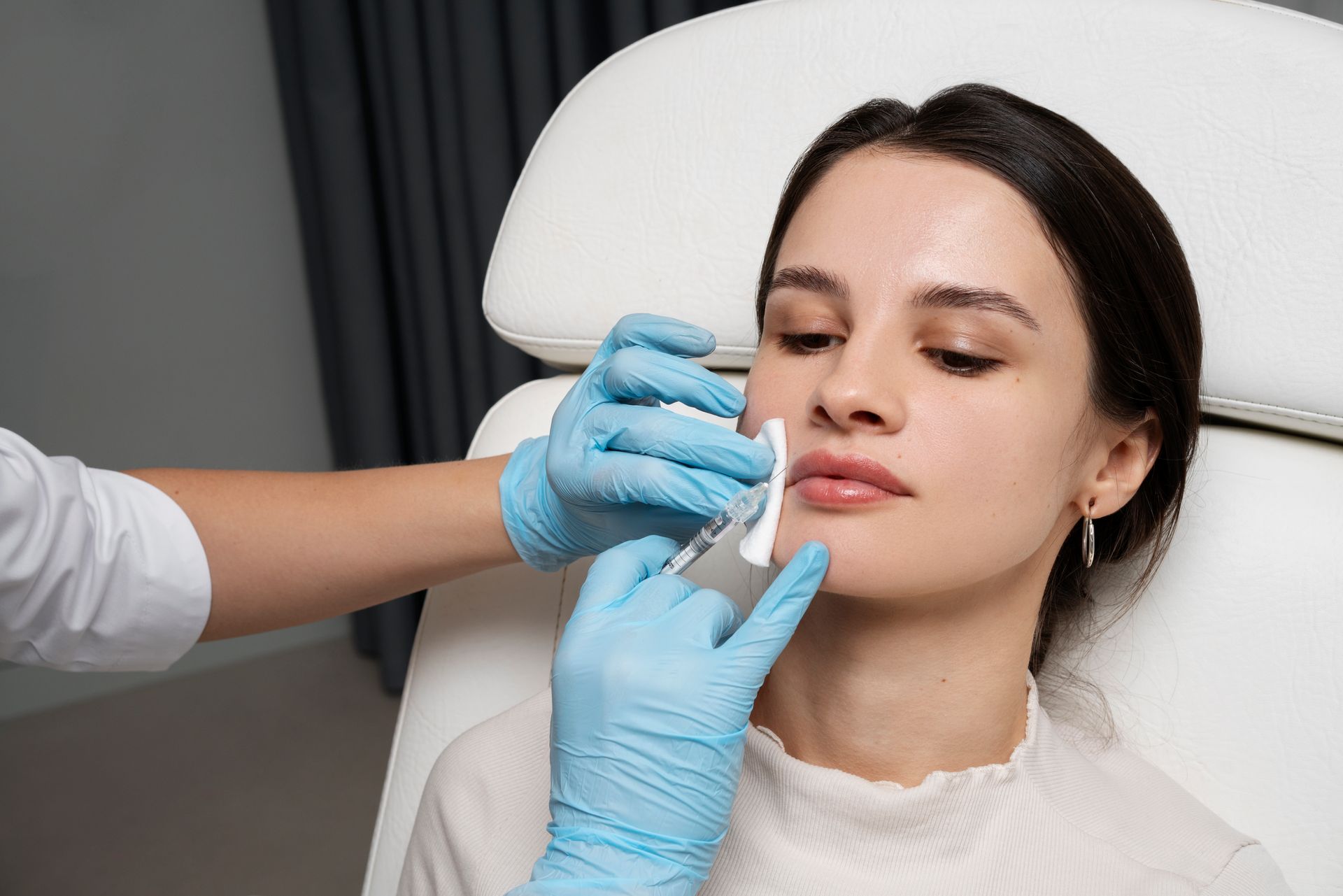 A woman is getting a botox injection in her lips.