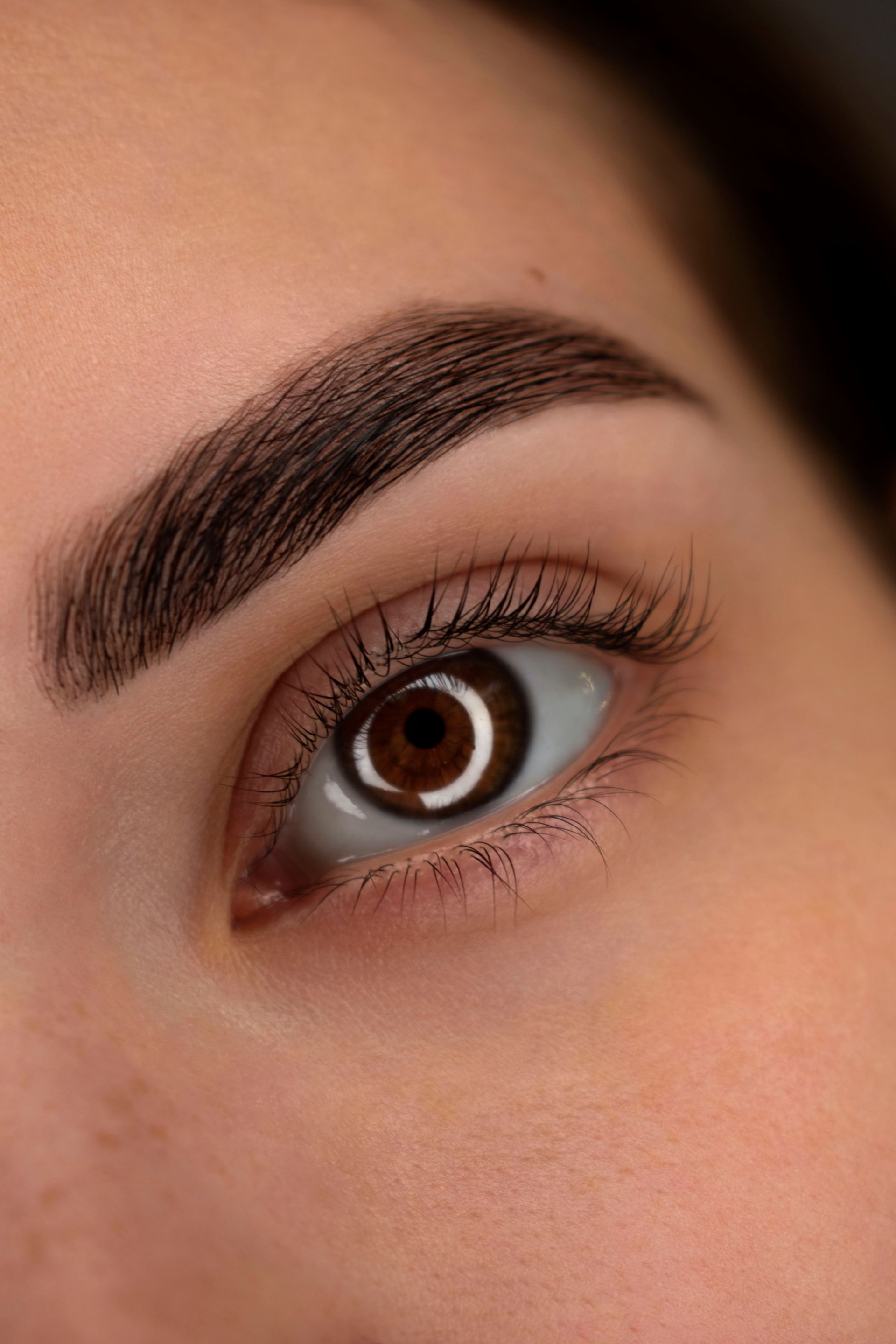 A close up of a woman 's eye with brown eyebrows.