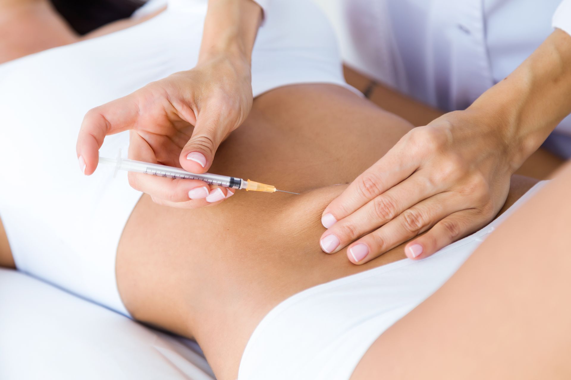 A woman is getting an injection in her stomach.