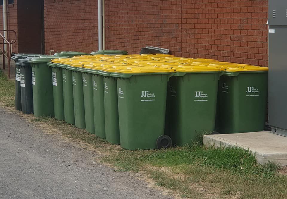 A Row of Green Garbage Cans With Yellow Lids — Bin in a Bath in Saint Albans Park, VIC