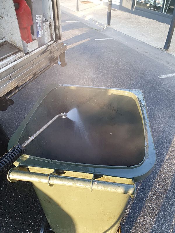 A Person Is Cleaning A Trash Can With A Hose — Bin in a Bath in Saint Albans Park, VIC