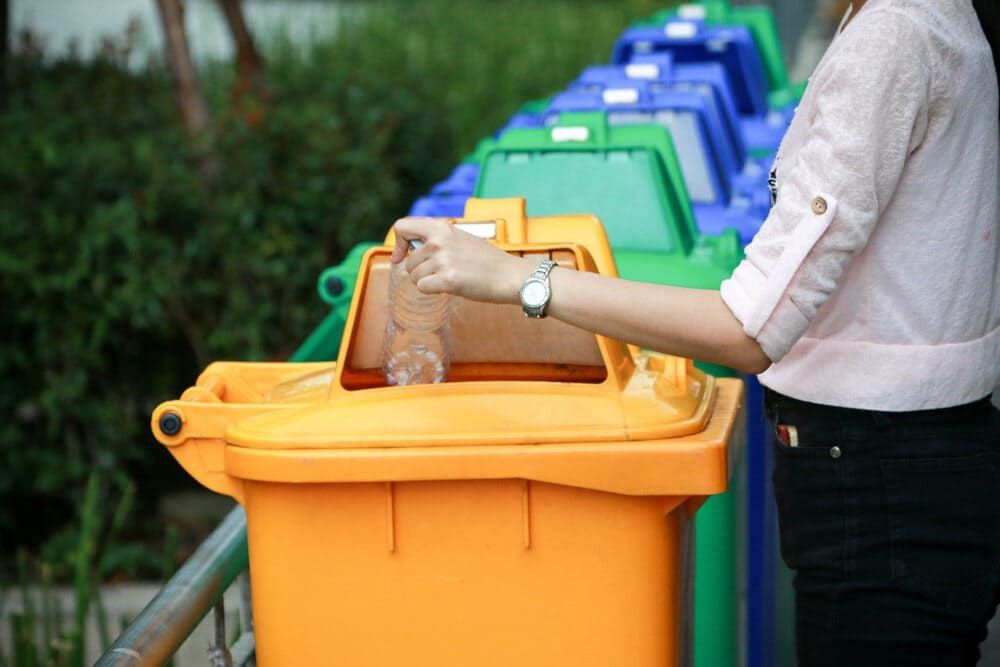 A Woman is Putting a Plastic Bottle Into a Yellow Trash Can — Bin in a Bath in Ballarat, VIC