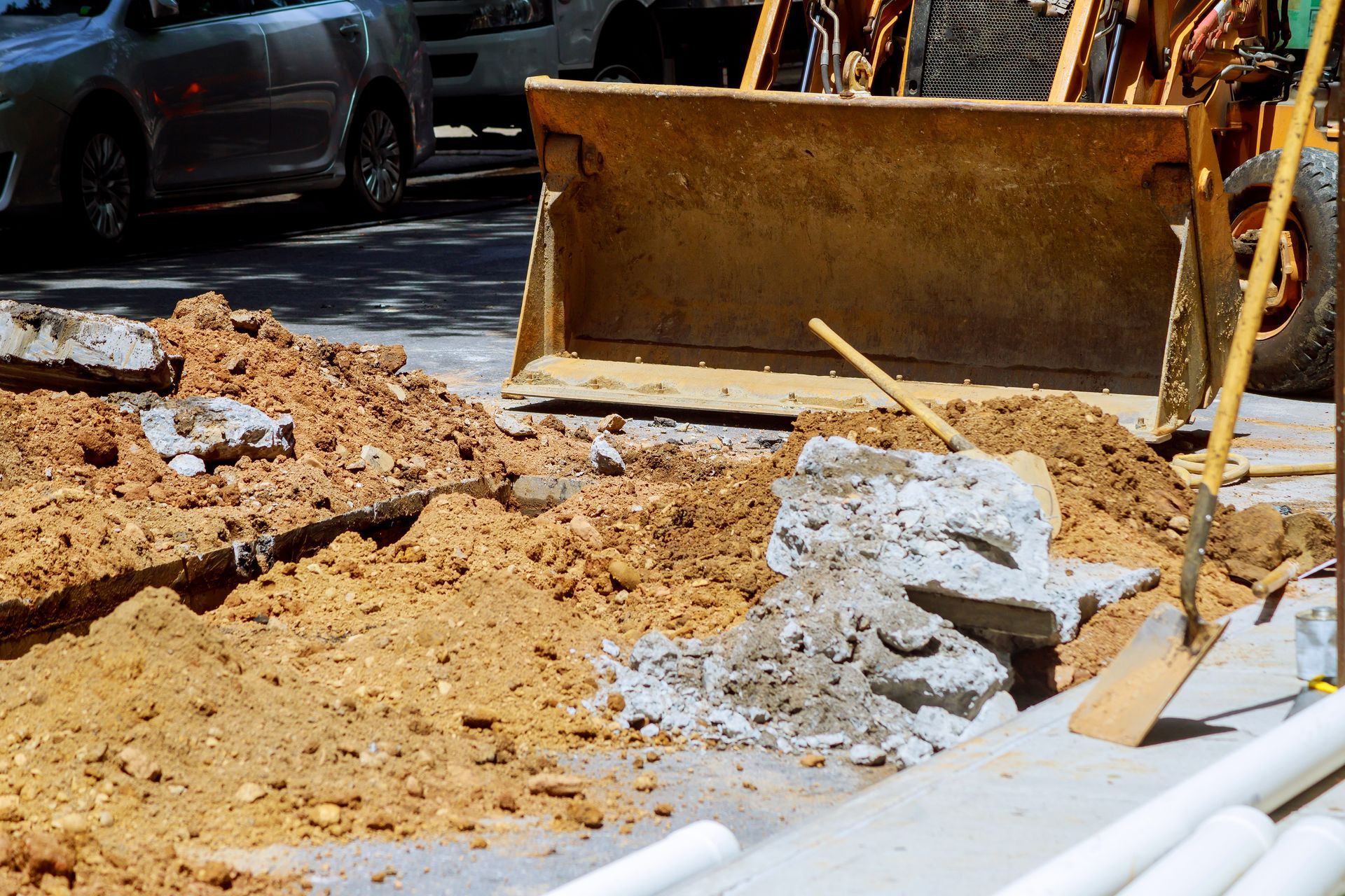Construction site with a bulldozer and dirt pile next to a road, broken concrete visible. Construction site with a bulldozer and dirt pile next to a road, broken concrete visible.