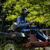 A man wearing a mask is riding a toro lawn mower