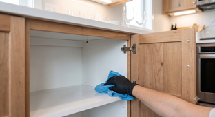 Three cleaners mopping a bright office space with shelves and cleaning supplies.