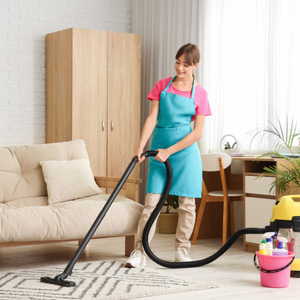 Woman vacuuming a living room with a black hose vacuum cleaner