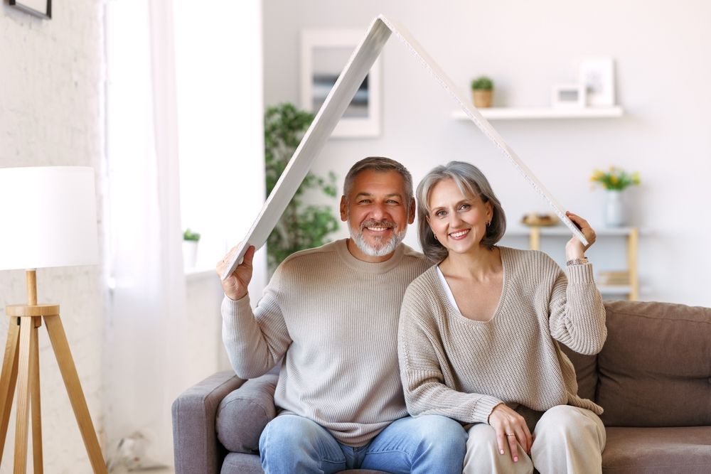 An elderly couple is sitting on a couch holding a large piece of wood.