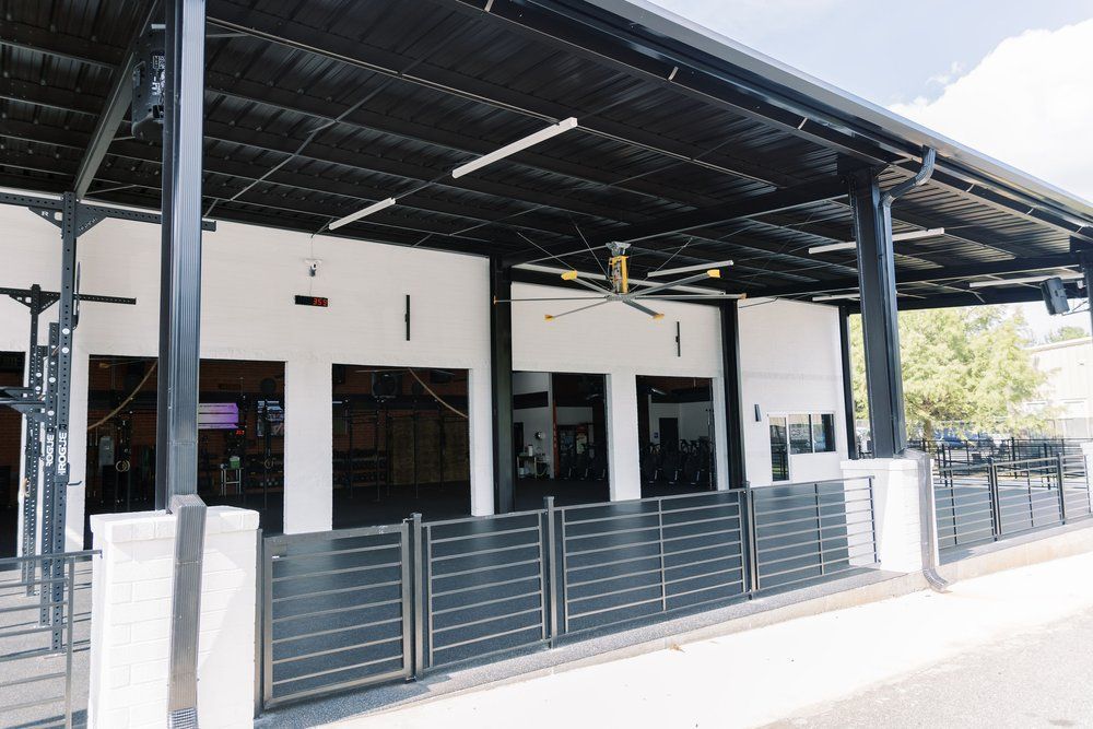 A white building with a black fence and a ceiling fan.