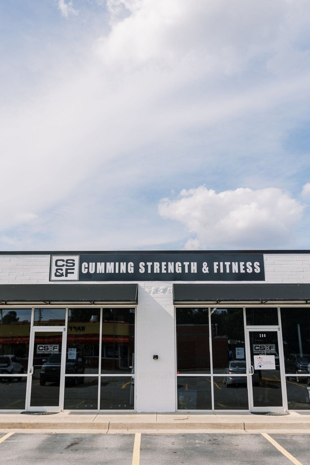 A building with a lot of windows and a sign that says cummings strength & fitness.