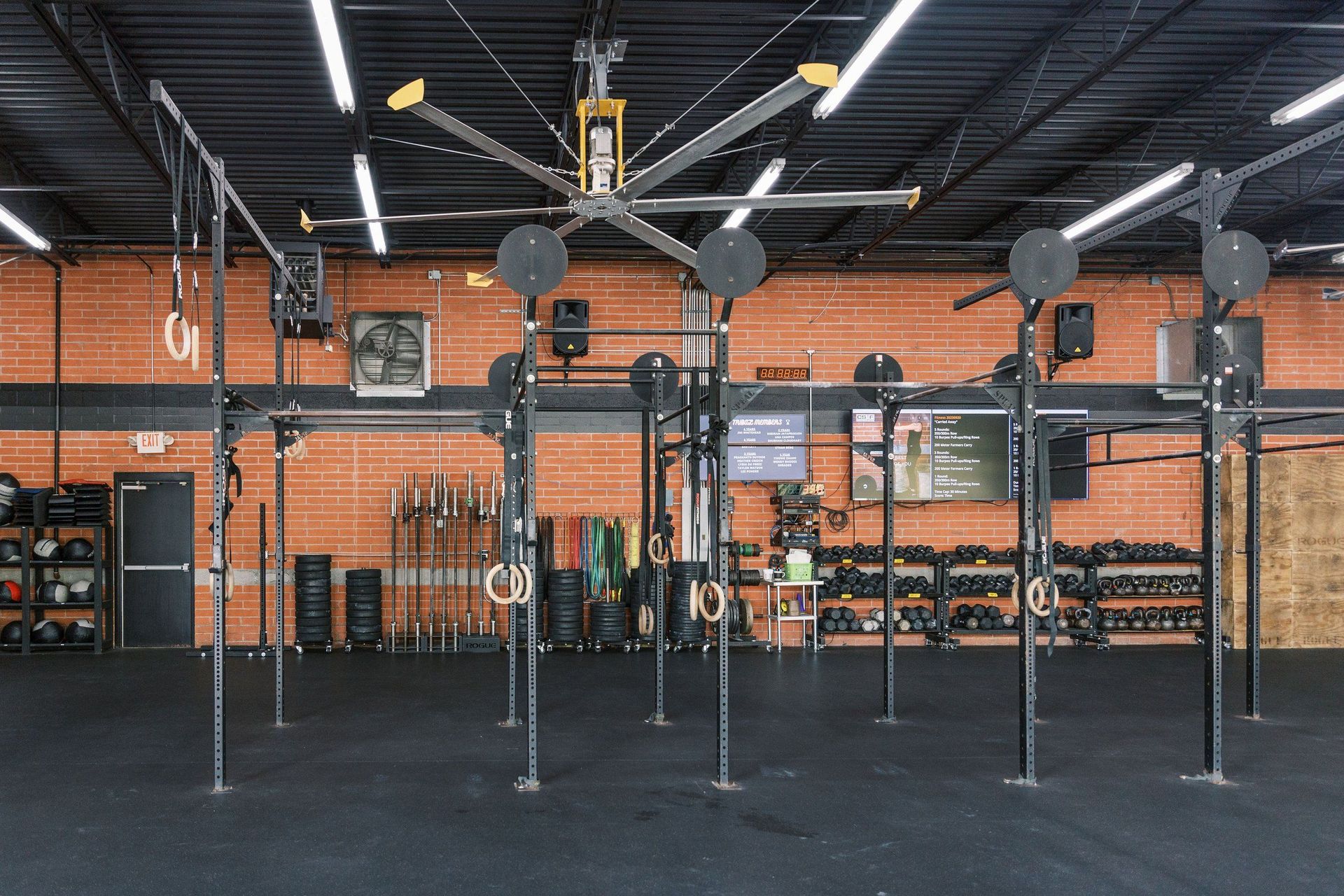 A large ceiling fan is hanging from the ceiling of a gym.