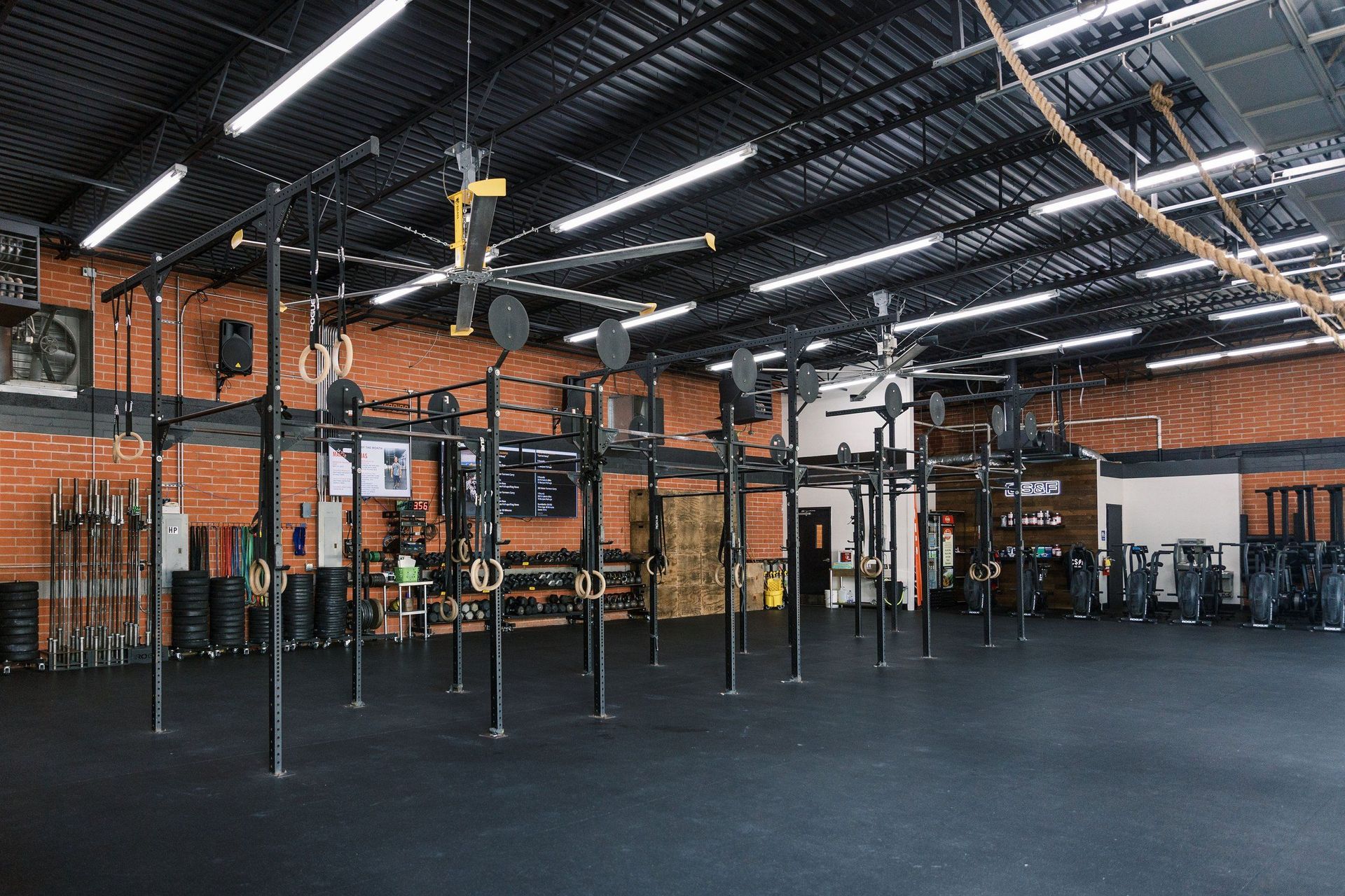 A large gym with a lot of equipment and a rope hanging from the ceiling.