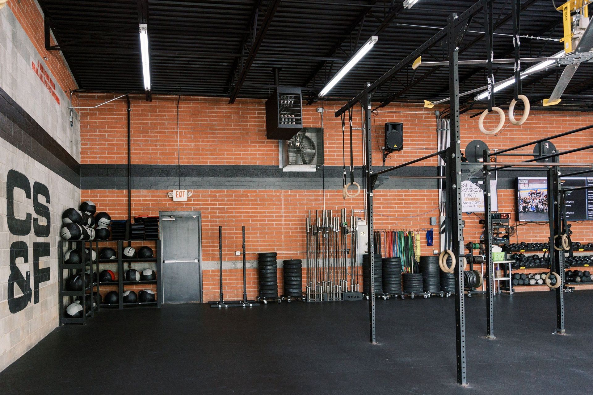 A gym with a lot of equipment and a brick wall.