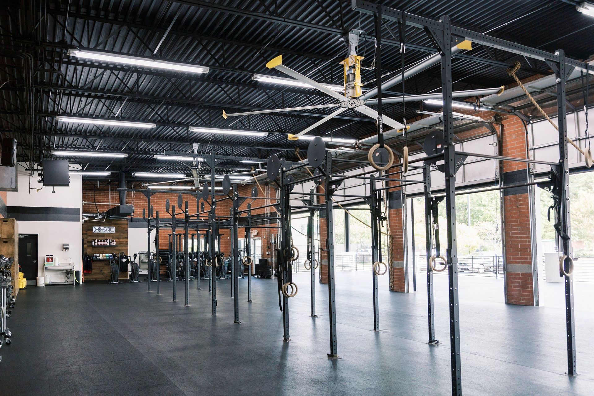 A large empty gym with a lot of fans hanging from the ceiling.