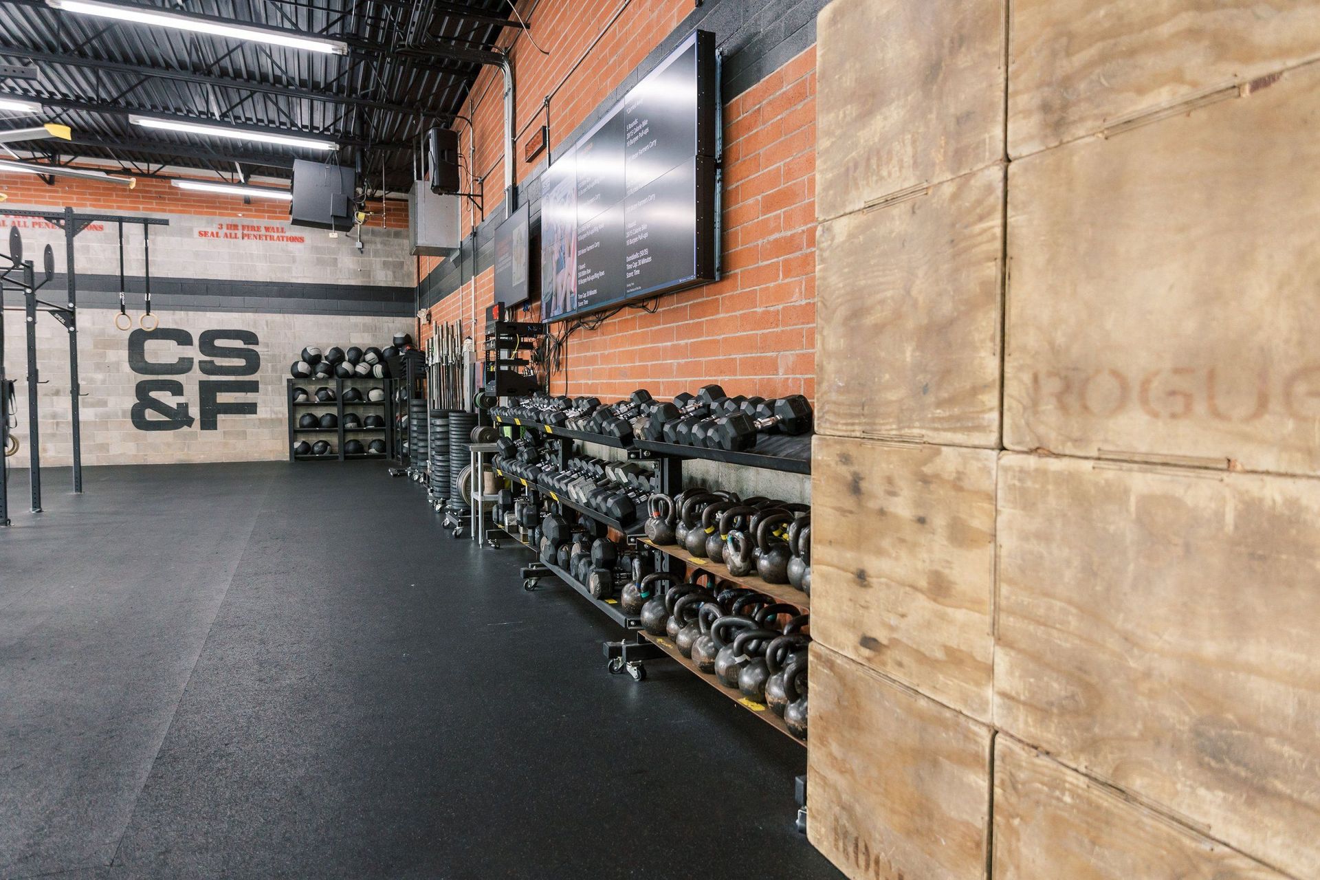 A gym with a lot of dumbbells and a wooden wall.