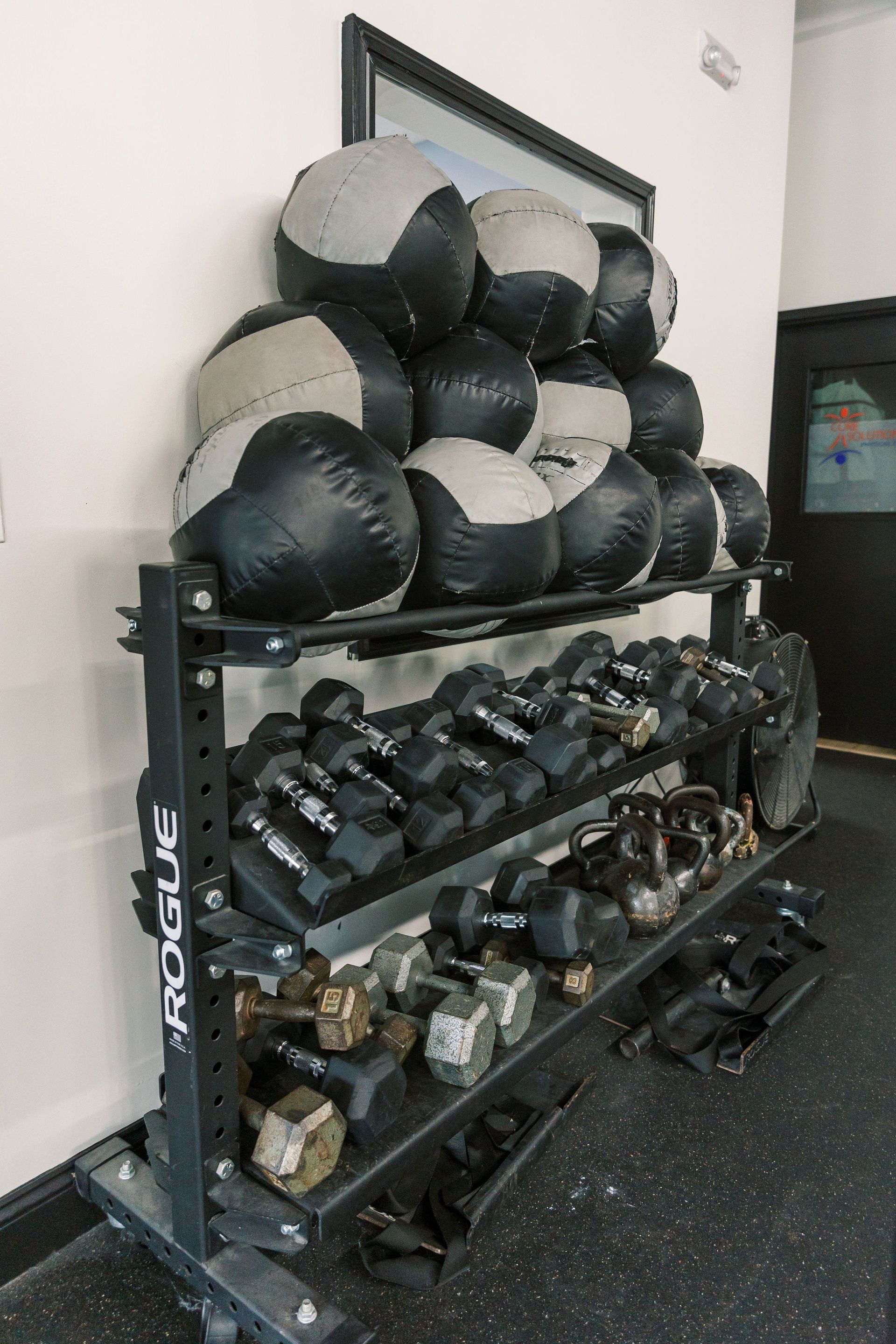 A rack of dumbbells and medicine balls in a gym.