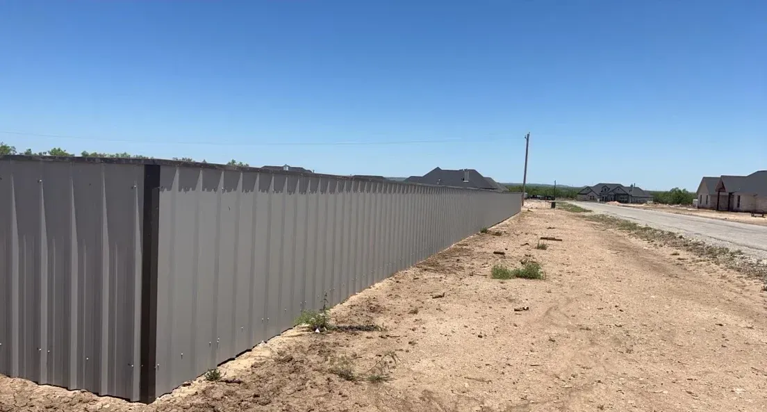 A fence is sitting on the side of a dirt road.