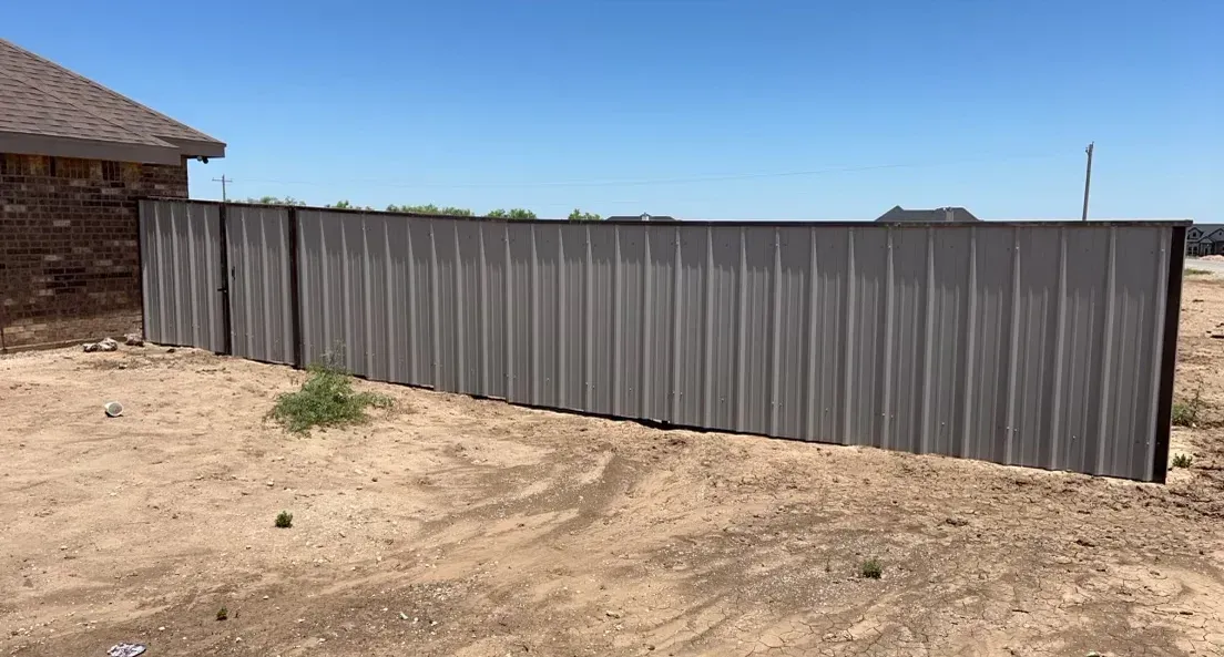 A metal fence is sitting in the middle of a dirt field.