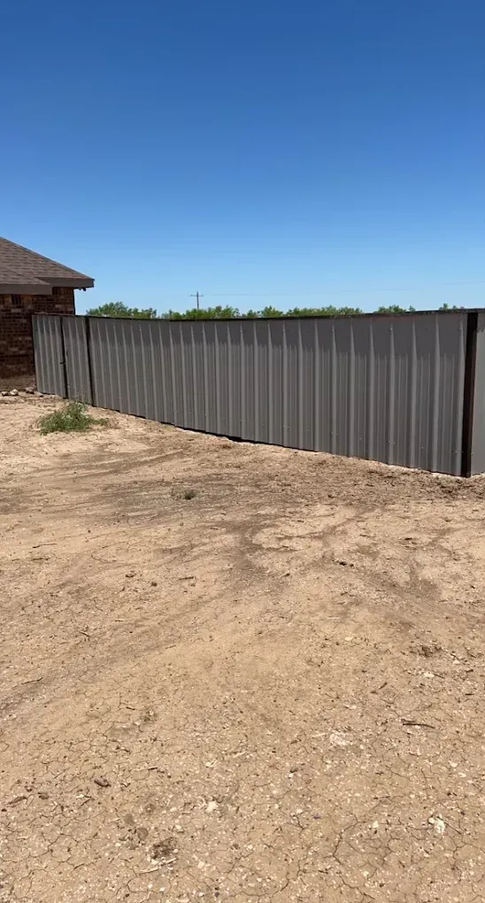 There is a fence in the middle of a dirt field.