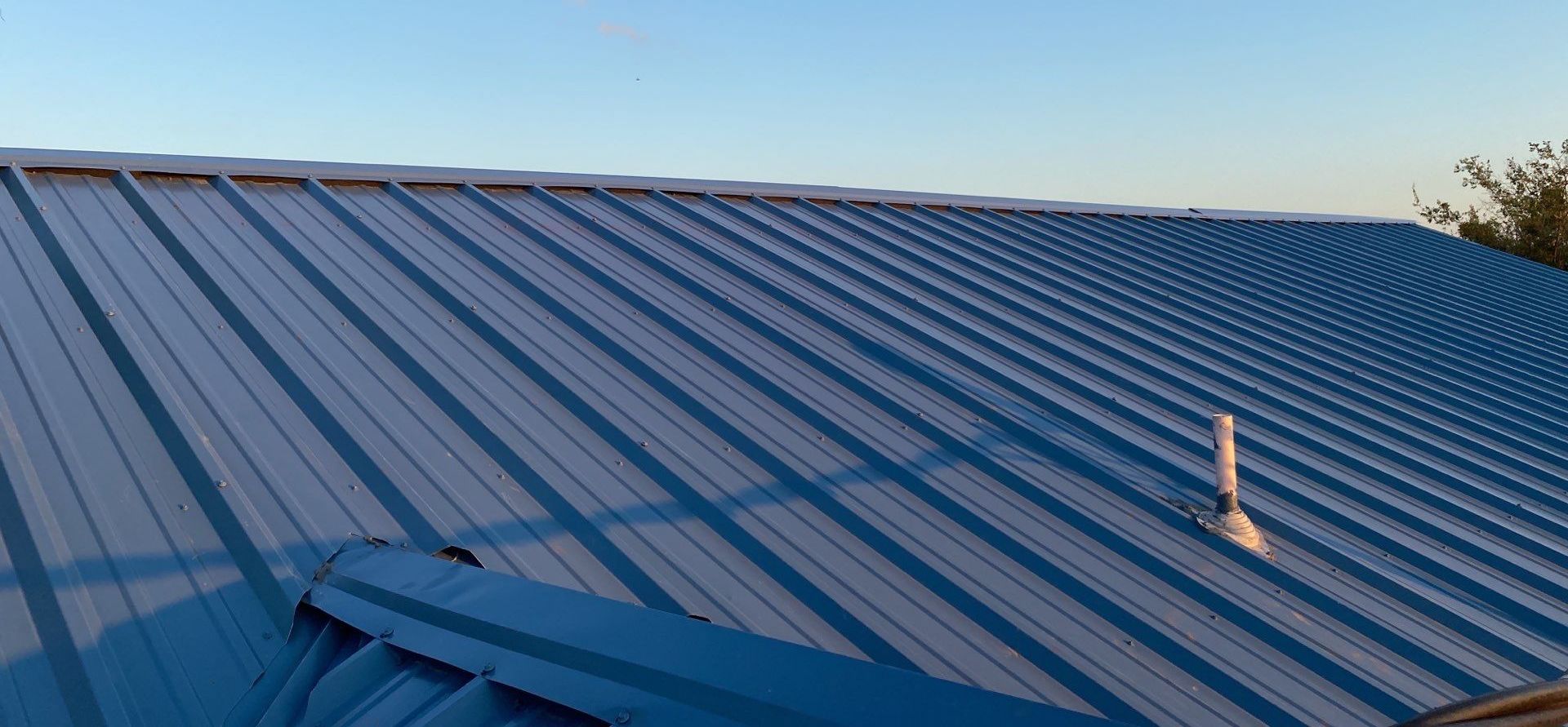 A blue metal roof with a chimney on top of it.
