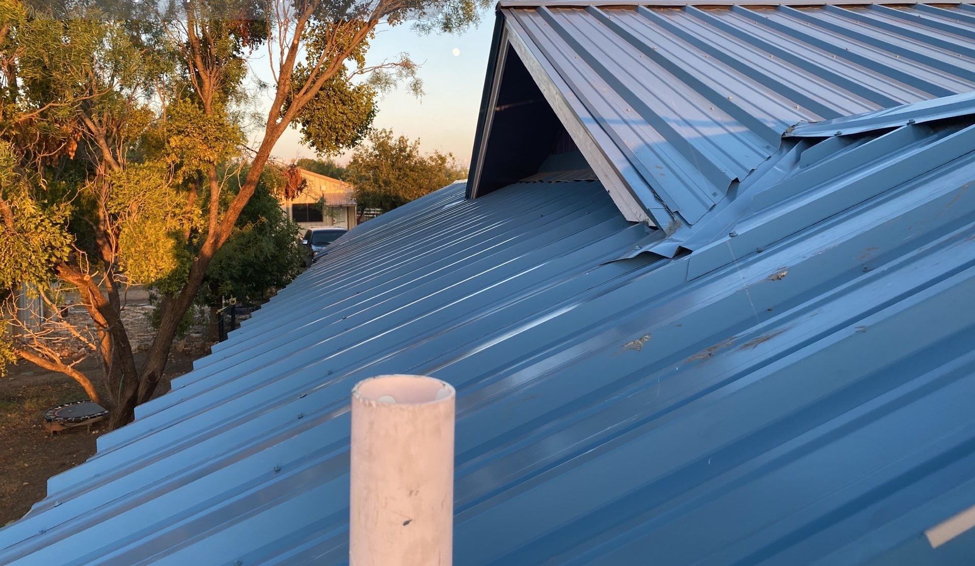 A blue metal roof with trees in the background