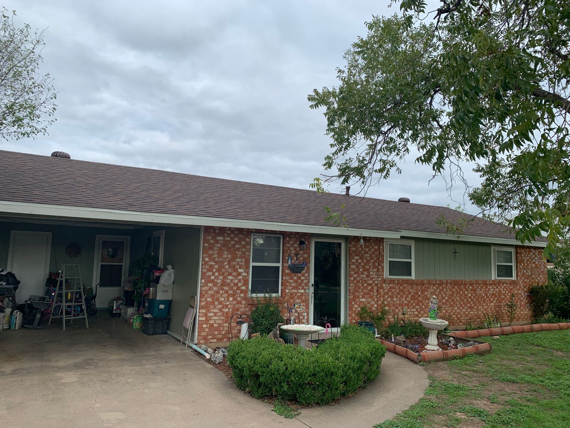A brick house with a covered porch and a fountain in front of it.