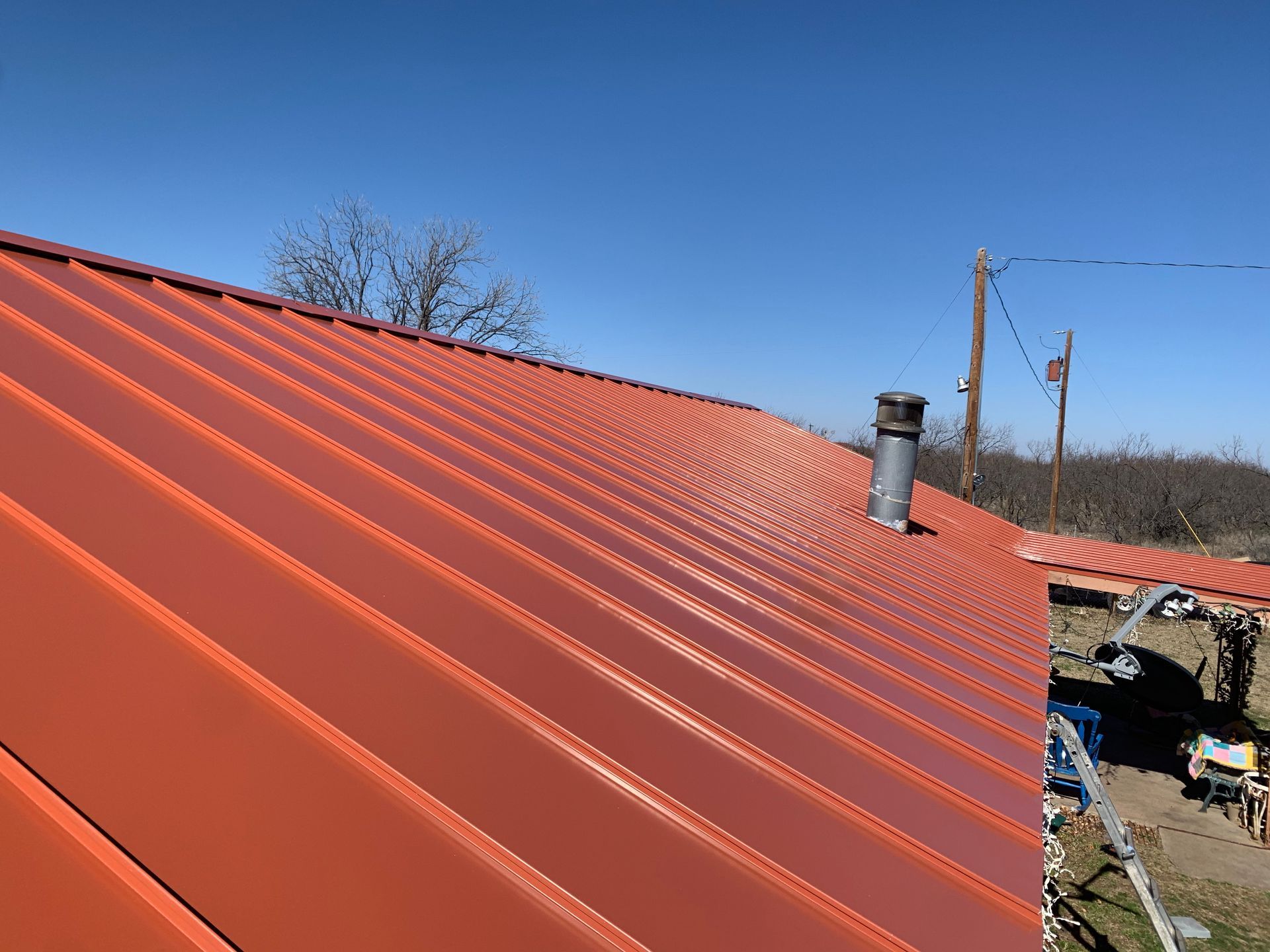 A red metal roof with a chimney on top of it.