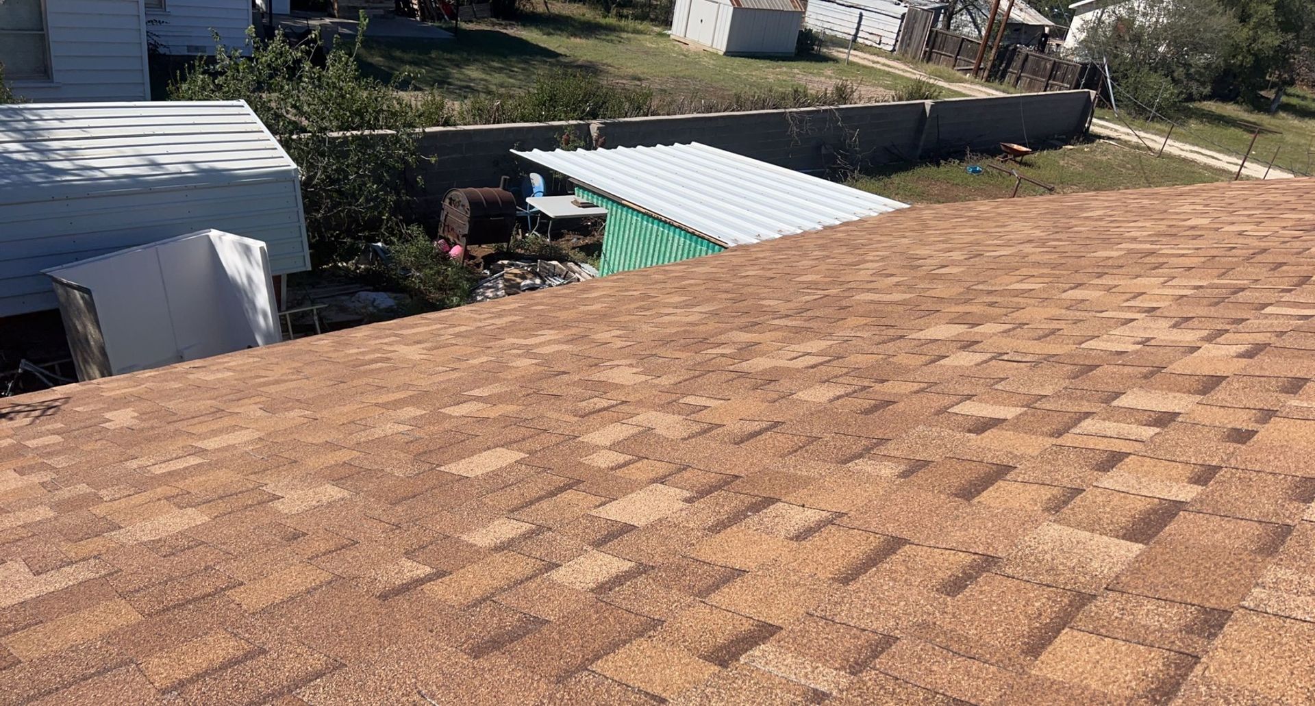 A close up of a roof with a shed in the background.