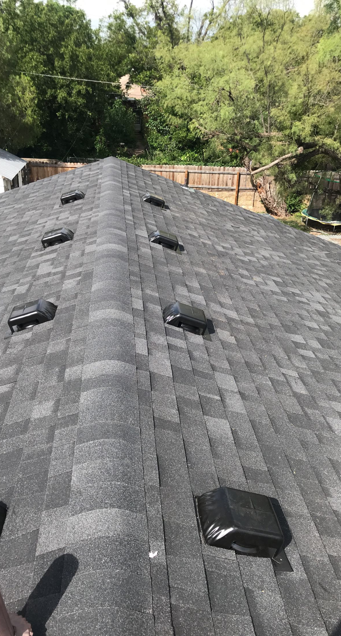 A roof with a lot of vents on it and trees in the background.