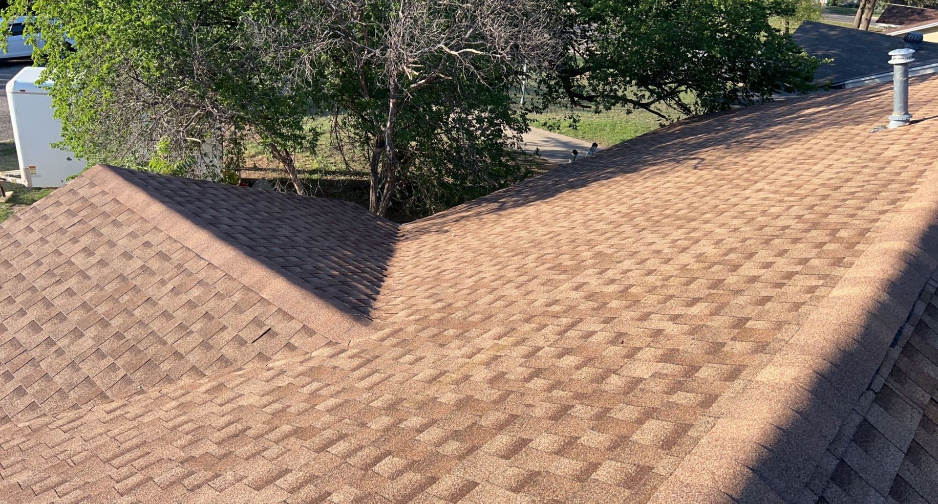 A close up of a roof with trees in the background.