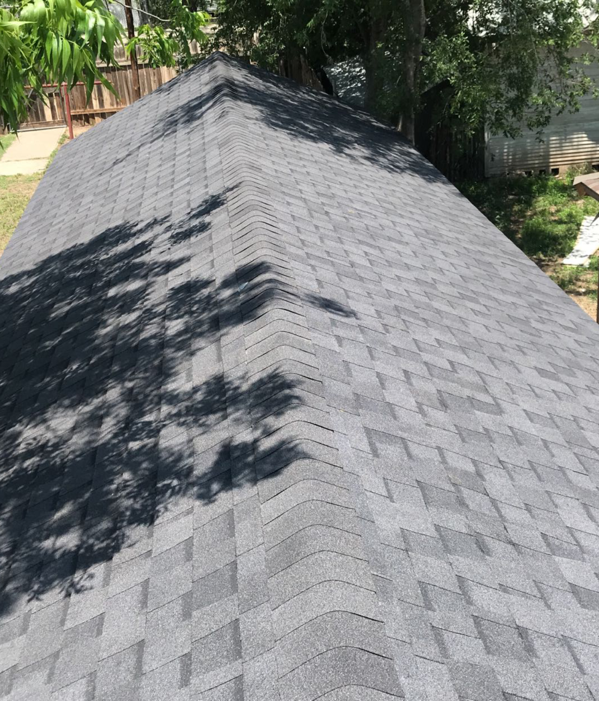 A roof with a lot of shingles on it and trees in the background.
