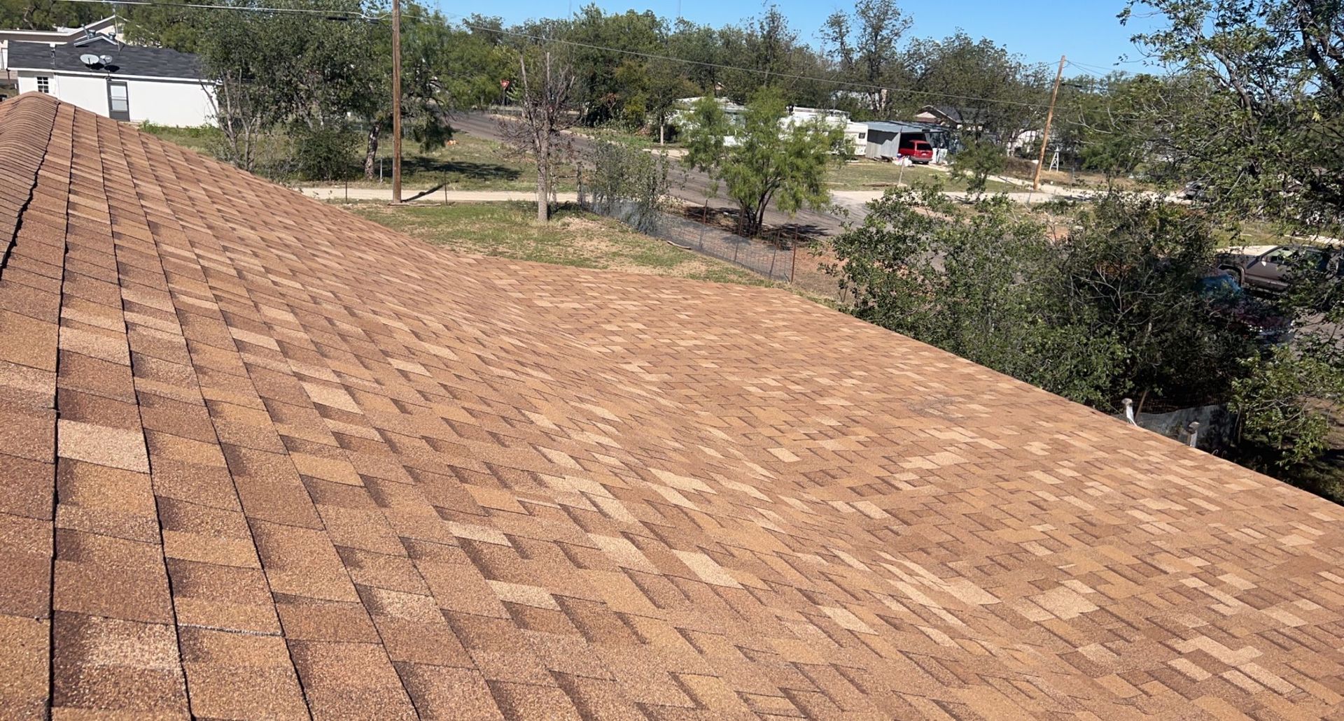 A roof with a lot of shingles on it and trees in the background.