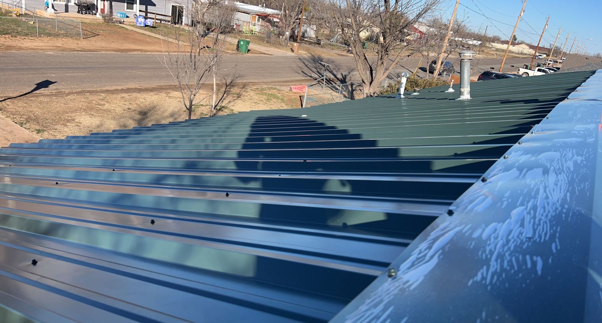 A close up of a metal roof with a shadow of a car on it.