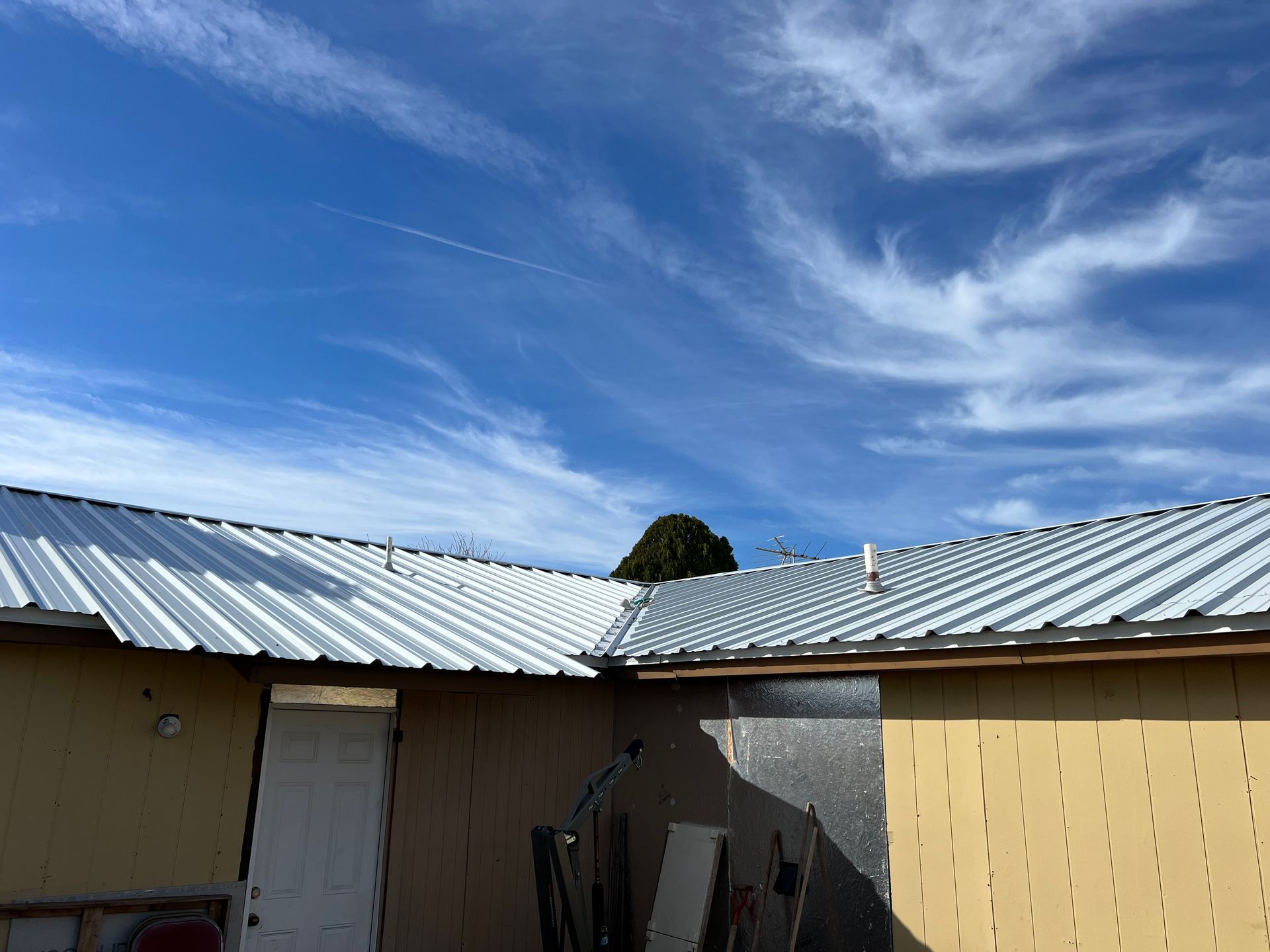 A house with a metal roof and a blue sky in the background.
