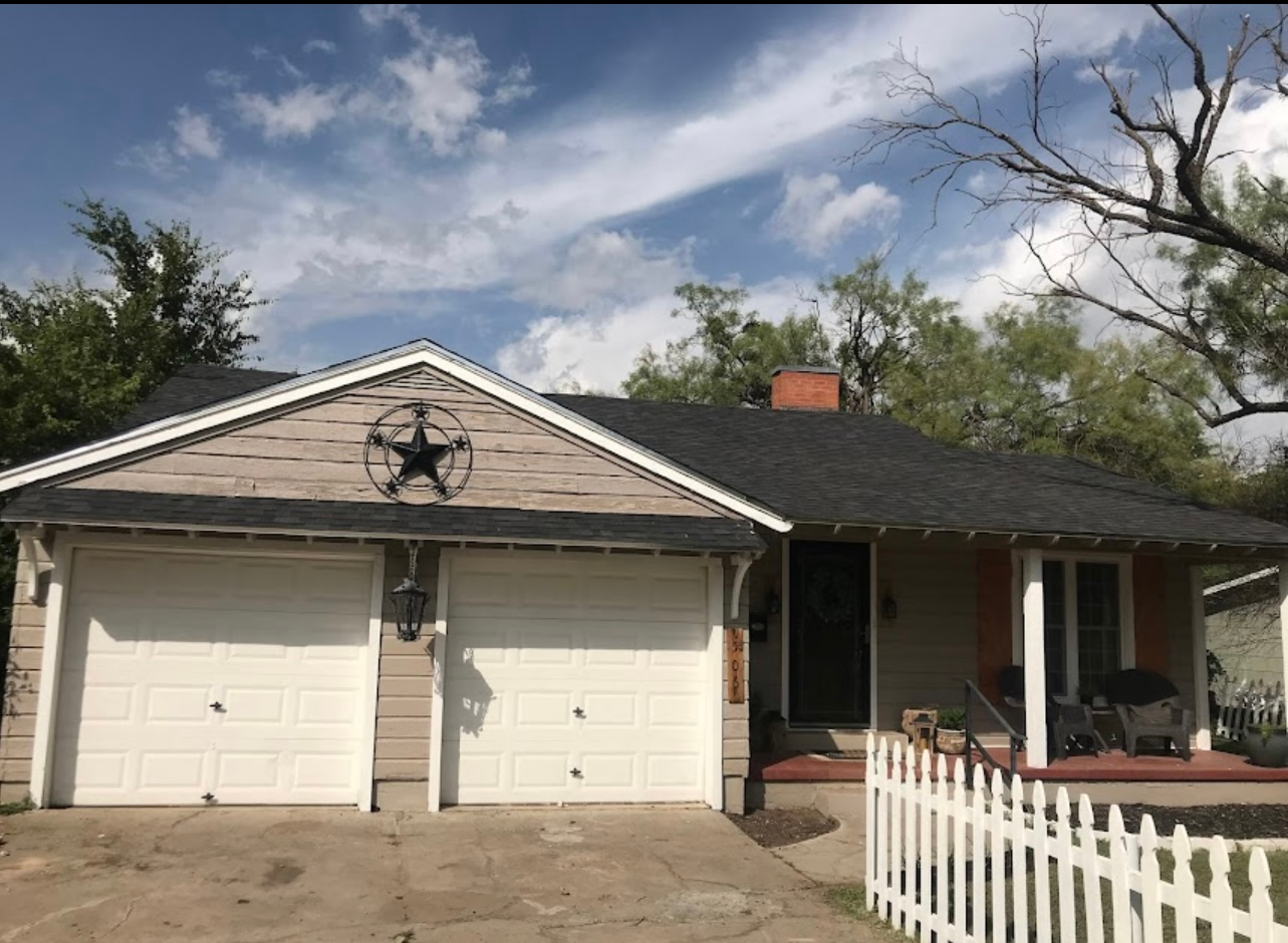 A house with two garage doors and a white picket fence