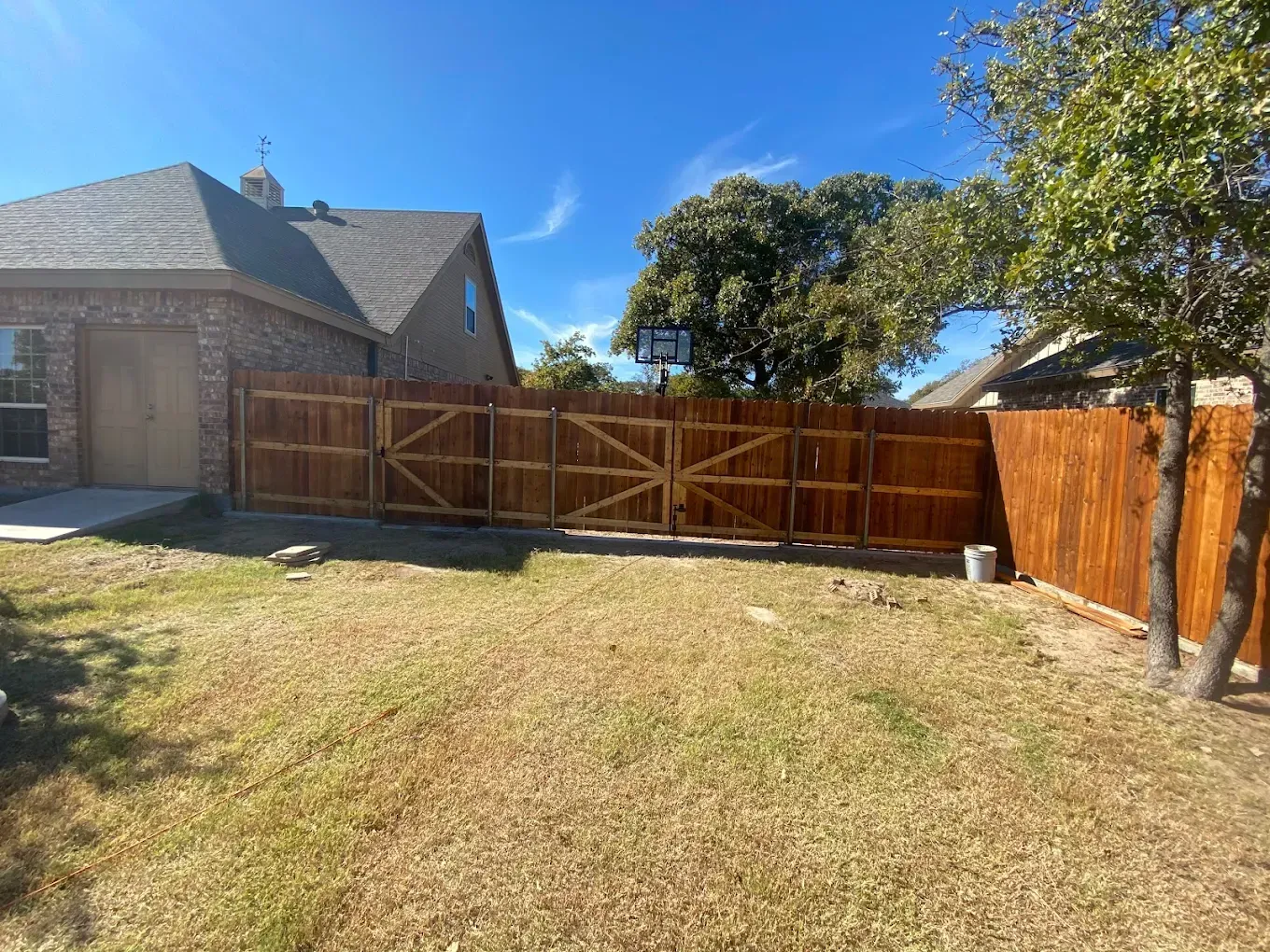 A wooden fence is in the backyard of a house.
