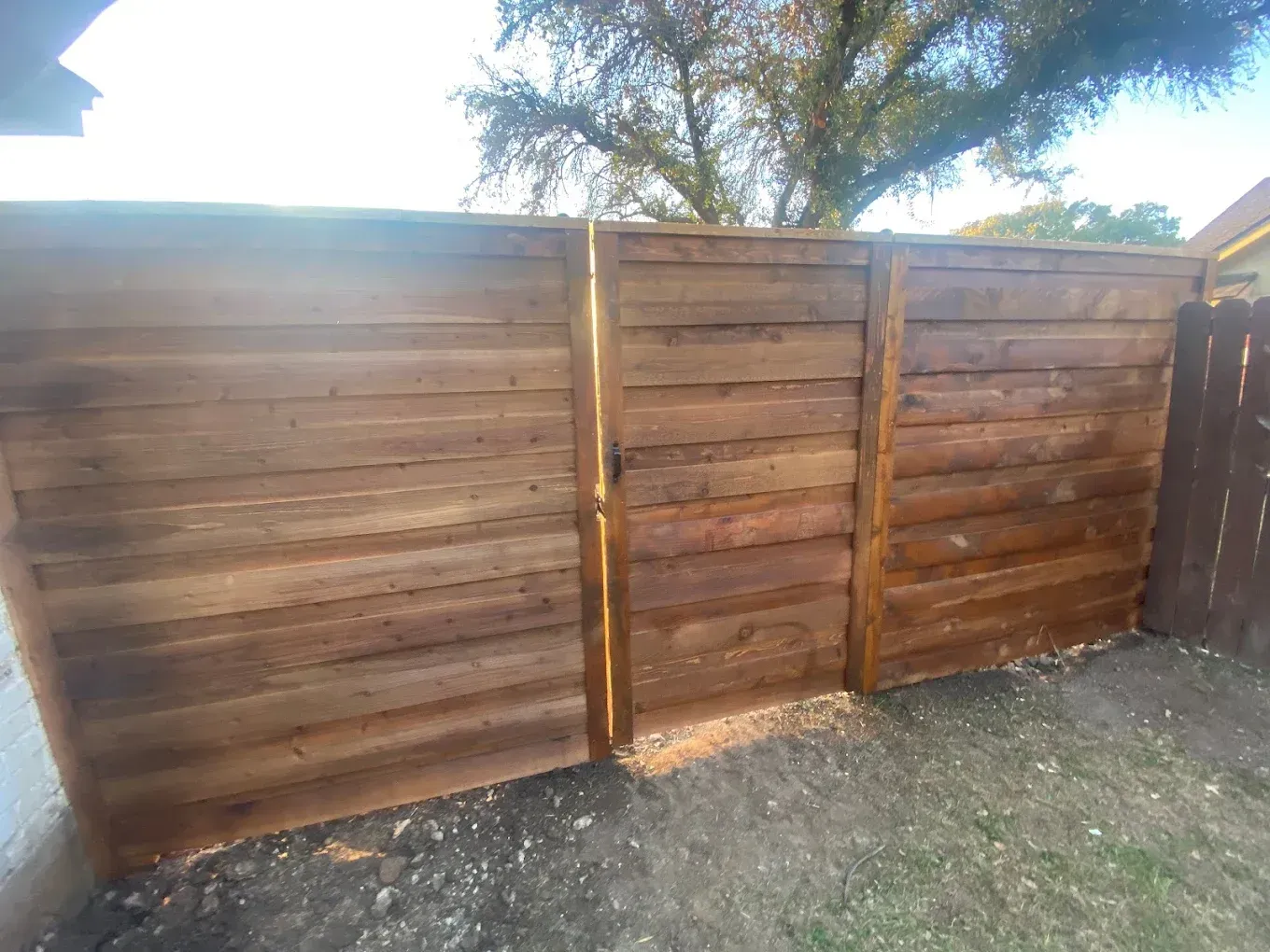 A wooden fence with a gate in the backyard.