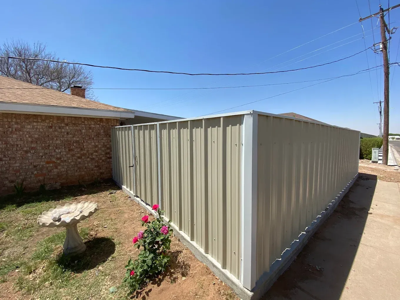 A house with a fence and a bird bath in front of it.