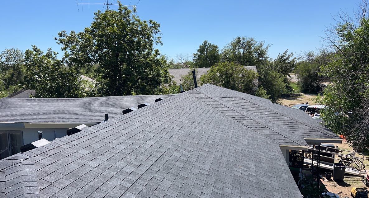 A roof with a lot of shingles on it and trees in the background.