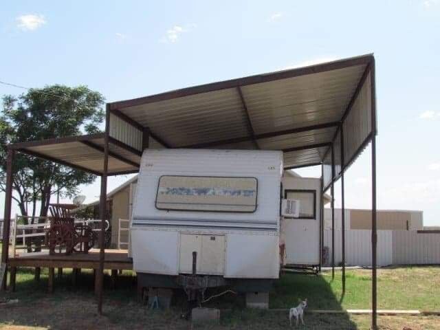 A white rv is parked under a metal canopy