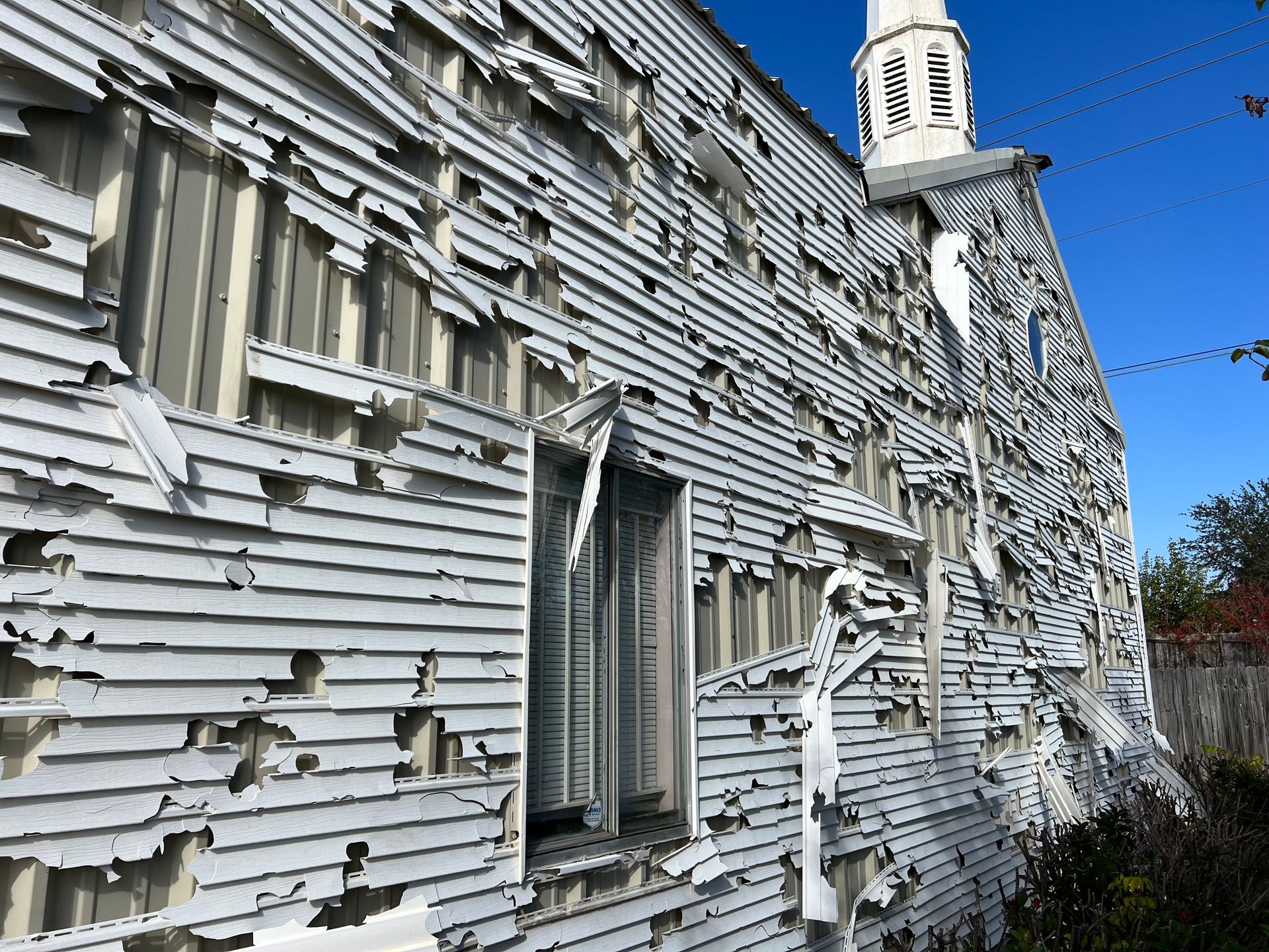 A white building with peeling paint and a clock tower