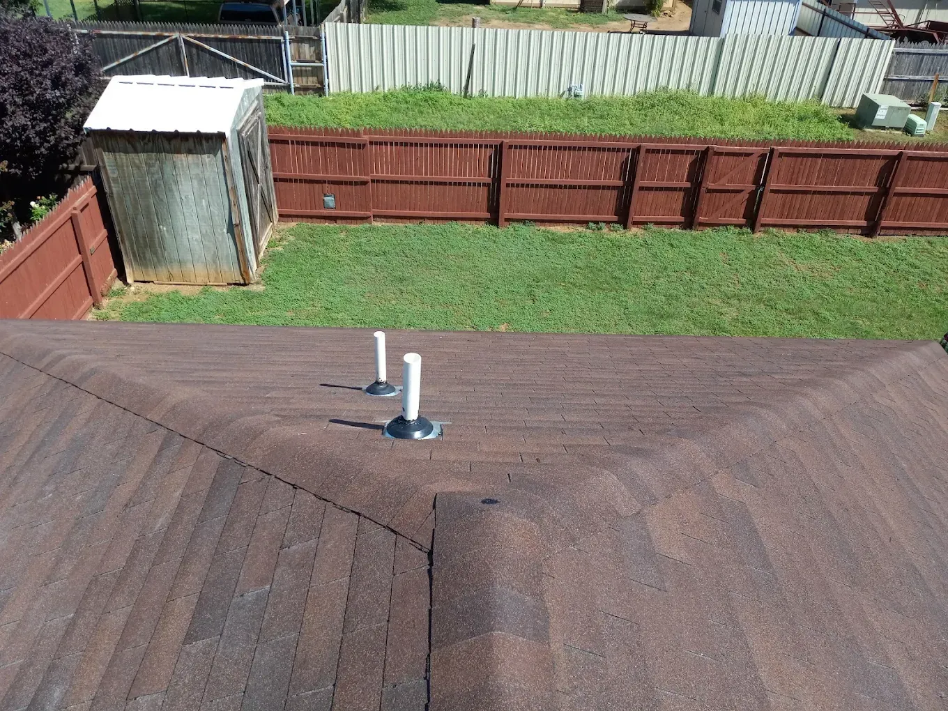 An aerial view of a roof with a fence in the background