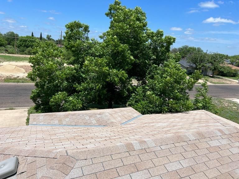 A roof with a tree in the background and a blue sky